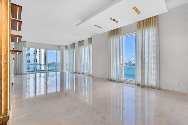 spare room featuring a wealth of natural light, light tile flooring, and a water view