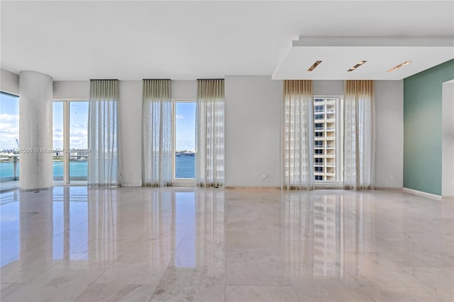 tiled spare room featuring a water view