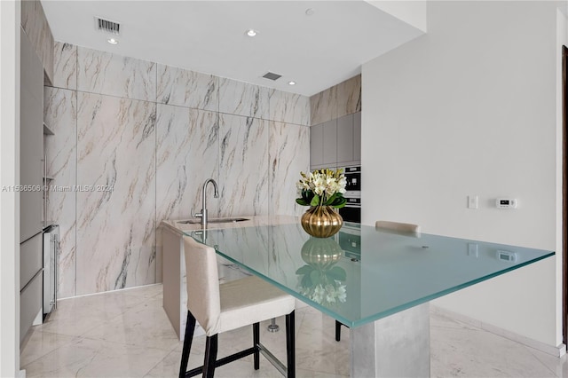 dining space featuring tile walls, sink, and light tile floors