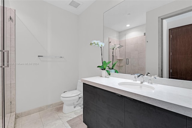 bathroom with a shower with shower door, vanity with extensive cabinet space, tile flooring, and toilet