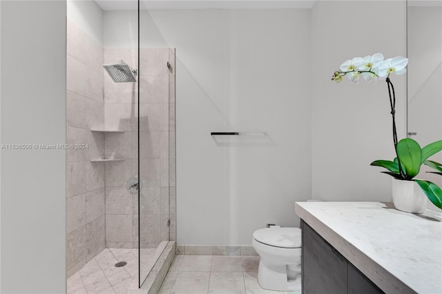 bathroom featuring a tile shower, tile flooring, vanity, and toilet