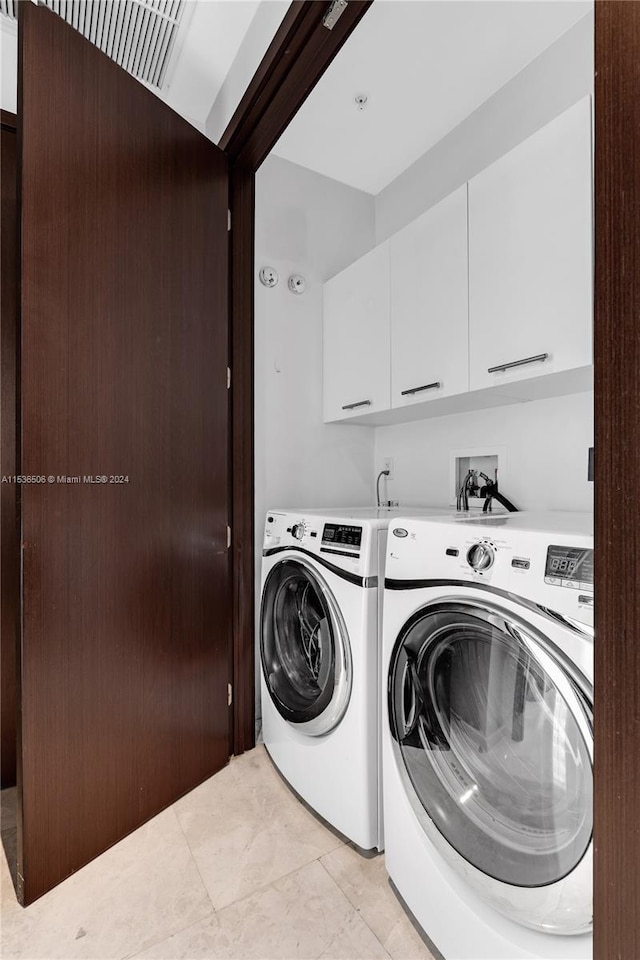 washroom featuring cabinets, washing machine and dryer, light tile floors, and washer hookup