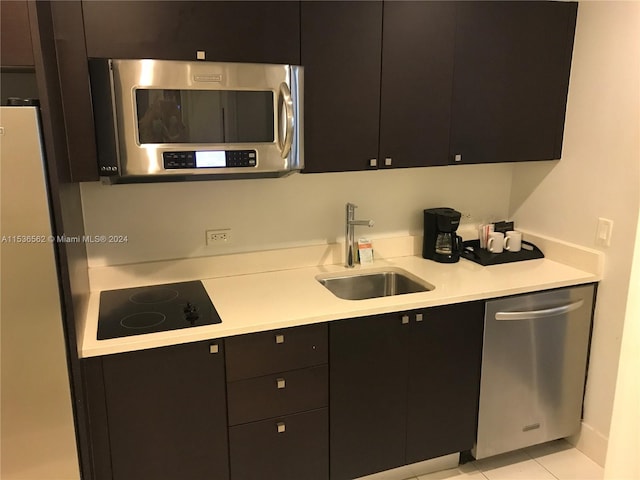 kitchen featuring light tile floors, appliances with stainless steel finishes, dark brown cabinets, and sink