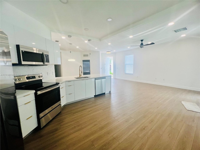 kitchen with stainless steel appliances, ceiling fan, white cabinetry, light wood-type flooring, and sink