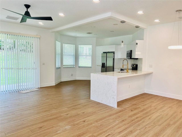 kitchen featuring white cabinets, appliances with stainless steel finishes, light hardwood / wood-style floors, and pendant lighting