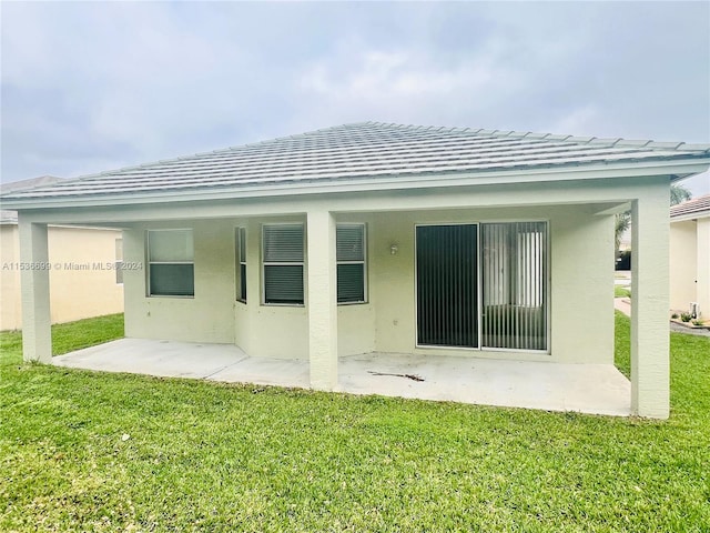 back of property with a yard and a patio