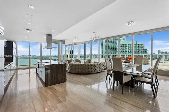 dining area featuring plenty of natural light, expansive windows, a water view, and light wood-type flooring