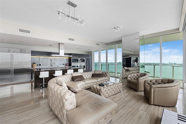 living room featuring track lighting, floor to ceiling windows, a water view, and light wood-type flooring