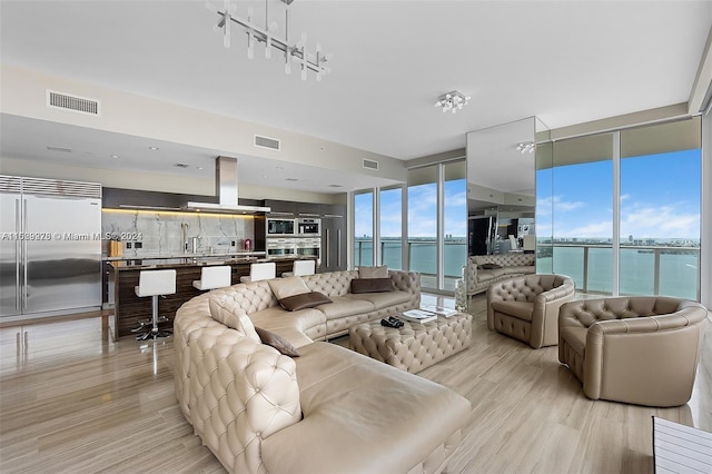 living room with expansive windows, a water view, a healthy amount of sunlight, and light hardwood / wood-style flooring