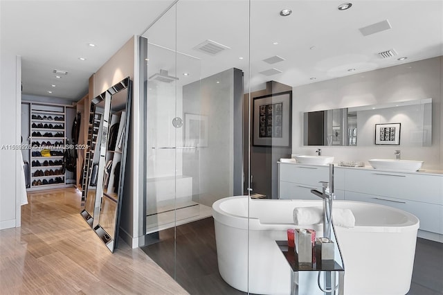 bathroom with dual bowl vanity, separate shower and tub, and wood-type flooring