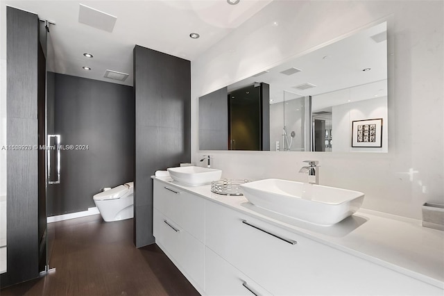 bathroom featuring oversized vanity, dual sinks, toilet, and wood-type flooring