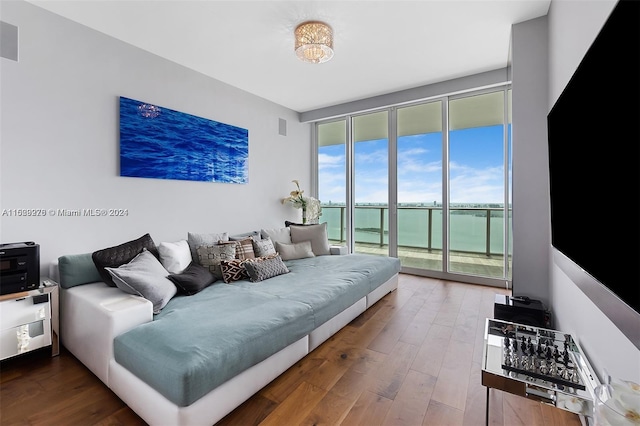 bedroom with access to exterior, a wall of windows, dark wood-type flooring, and a water view