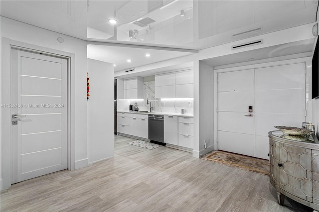 kitchen featuring dishwasher, light wood-type flooring, white cabinetry, and backsplash