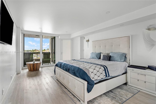 bedroom with access to exterior, light hardwood / wood-style flooring, and a wall of windows