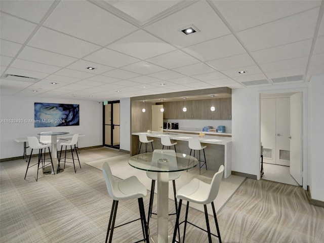 dining space with light colored carpet and a drop ceiling