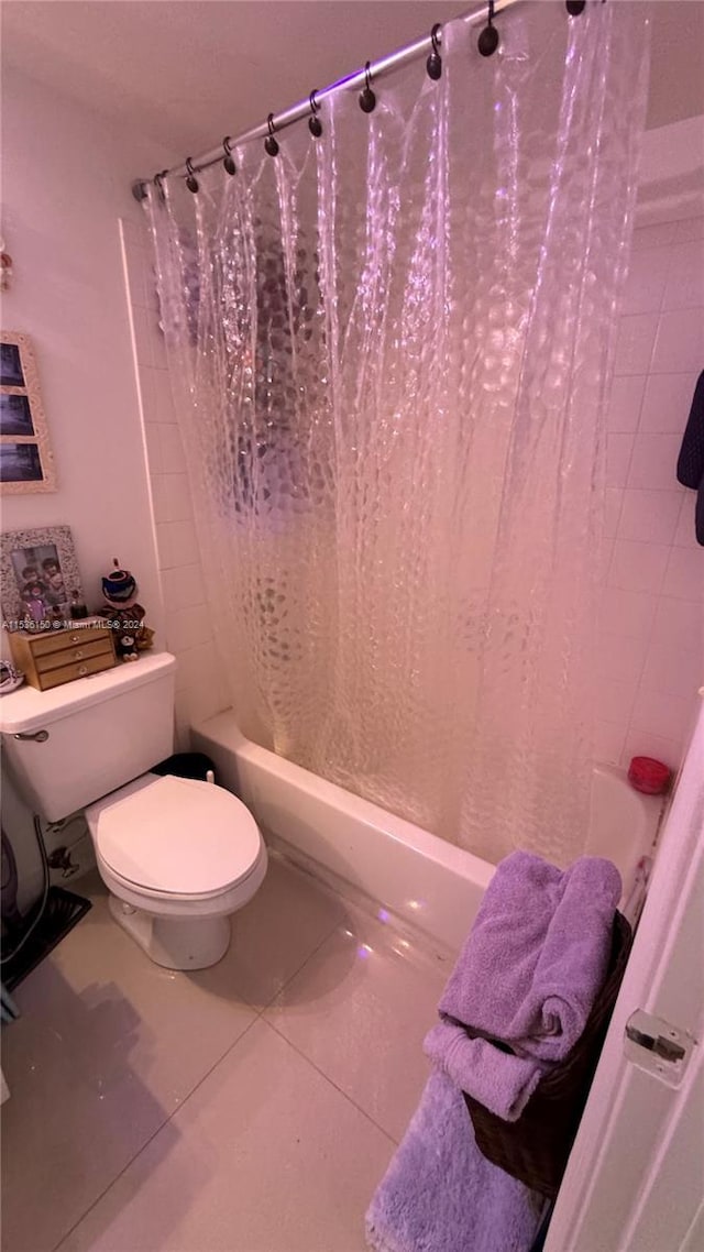 bathroom with shower / tub combo with curtain, tile patterned flooring, and toilet