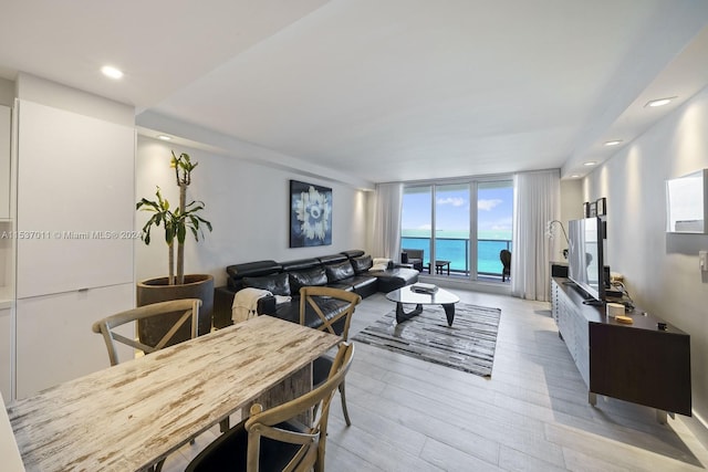 dining room featuring a water view, expansive windows, and light wood-type flooring