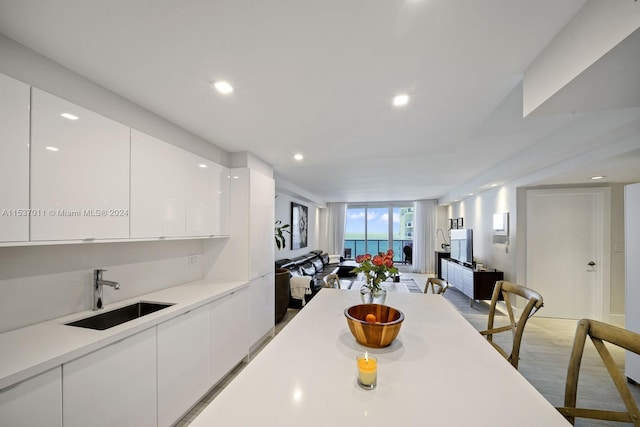 kitchen featuring white cabinets, a water view, hardwood / wood-style floors, and sink