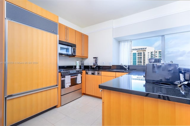 kitchen with light tile floors, kitchen peninsula, range with electric cooktop, and paneled built in refrigerator