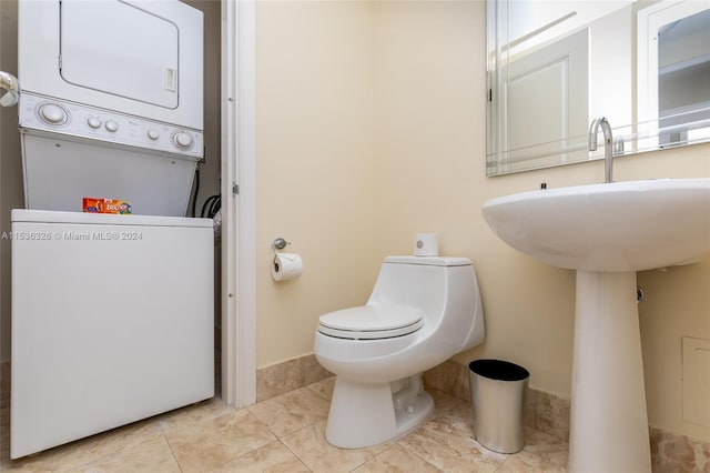 bathroom featuring toilet, tile floors, and stacked washer and dryer