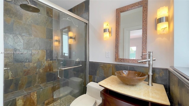 bathroom with tile walls, toilet, a shower with shower door, oversized vanity, and tasteful backsplash