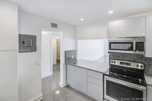 kitchen featuring stainless steel appliances, white cabinets, light tile floors, and stone counters