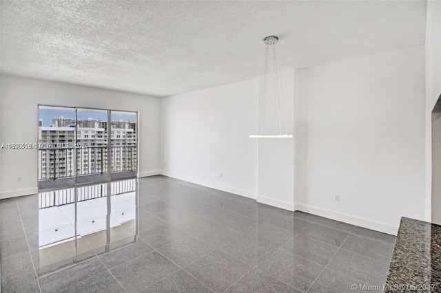 empty room featuring dark tile flooring and a textured ceiling