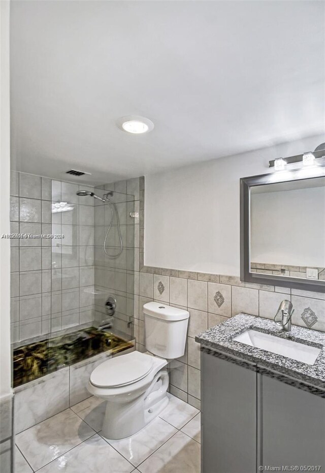 full bathroom with vanity, tile flooring, toilet, and tile walls