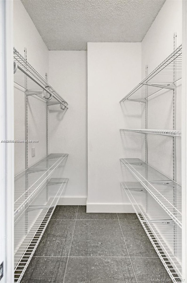 walk in closet with dark tile floors