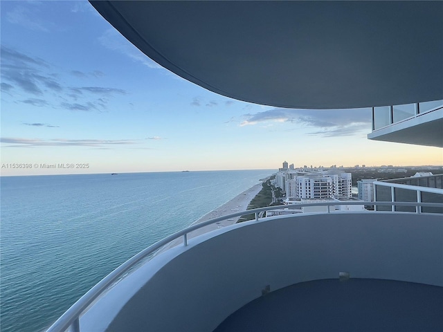 balcony at dusk featuring a water view