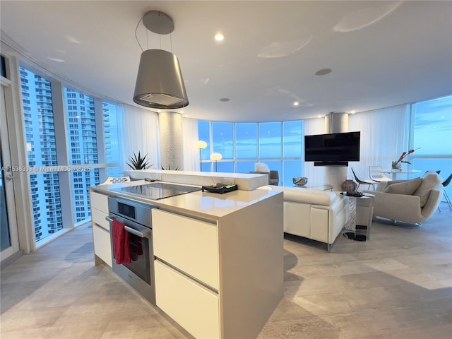 kitchen featuring black electric cooktop, pendant lighting, white cabinets, a center island, and oven