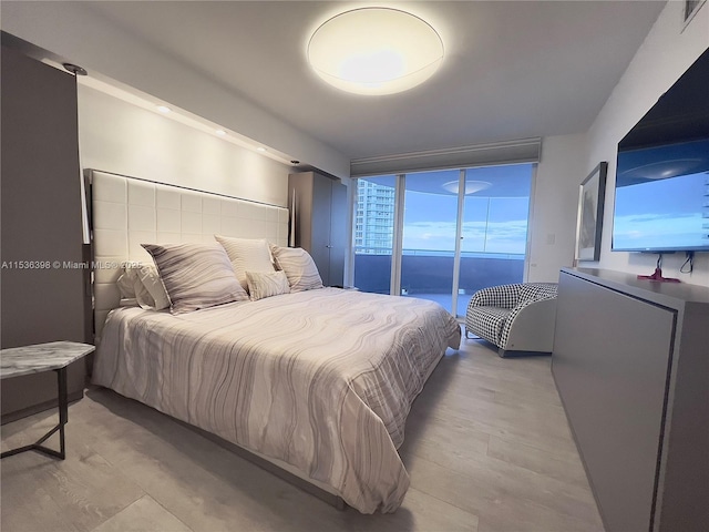 bedroom featuring access to outside, light hardwood / wood-style flooring, and expansive windows