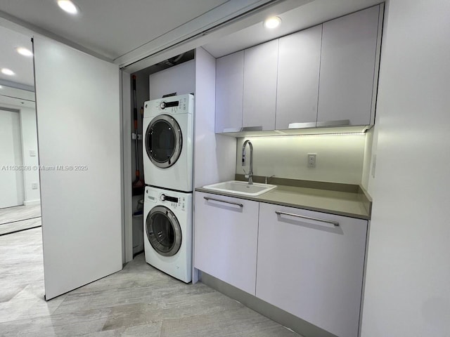 clothes washing area featuring sink and stacked washing maching and dryer