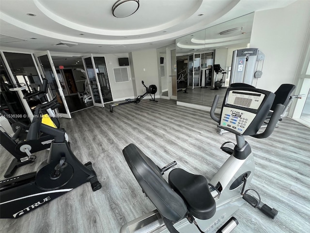 gym with hardwood / wood-style flooring and a raised ceiling