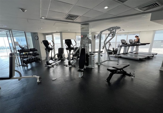 exercise room with a paneled ceiling and floor to ceiling windows