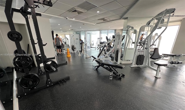 workout area featuring a paneled ceiling and a wall of windows