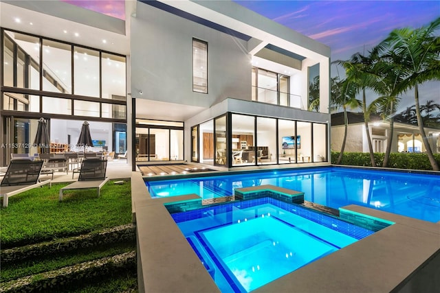 pool at dusk with a patio and an in ground hot tub