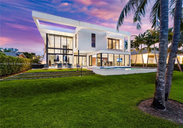 back house at dusk with a fenced in pool, a lawn, and a patio