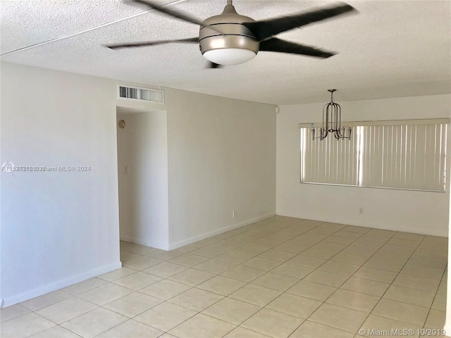 tiled spare room featuring a textured ceiling and ceiling fan with notable chandelier