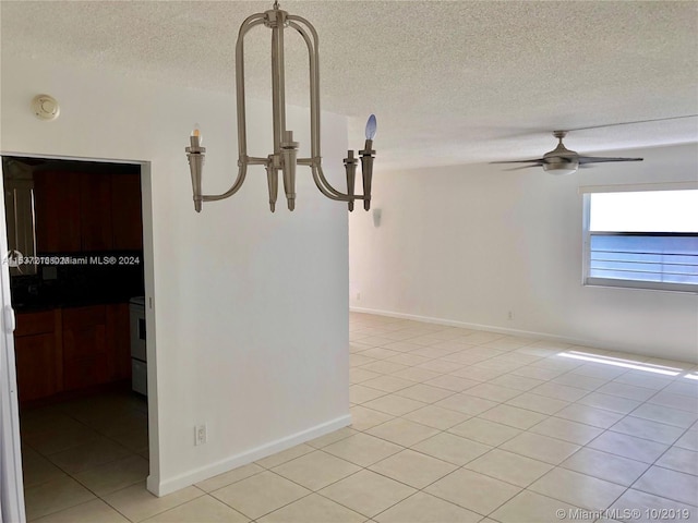 tiled empty room with a textured ceiling and ceiling fan with notable chandelier