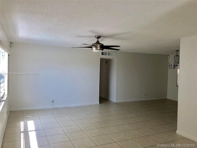 spare room with a textured ceiling, light tile flooring, and ceiling fan