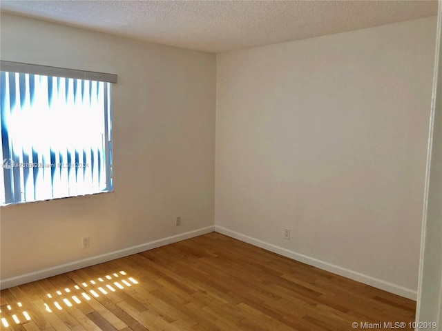 empty room featuring light hardwood / wood-style flooring, a textured ceiling, and a wealth of natural light