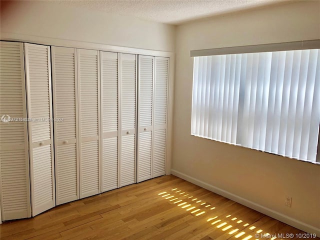 unfurnished bedroom featuring a closet, a textured ceiling, and light wood-type flooring