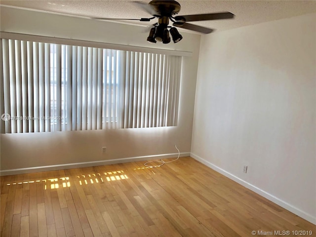 spare room with light hardwood / wood-style flooring, ceiling fan, and a textured ceiling