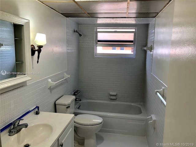 full bathroom featuring tile walls, tiled shower / bath combo, toilet, and vanity