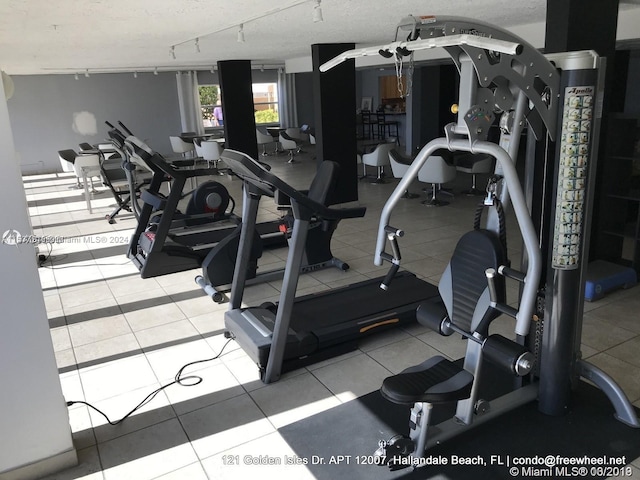 exercise room featuring light tile floors and track lighting