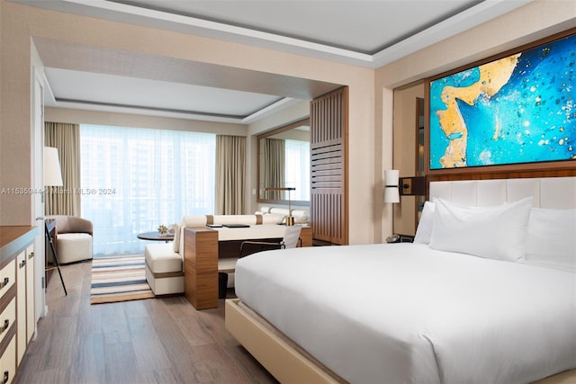 bedroom featuring a raised ceiling and light wood-type flooring