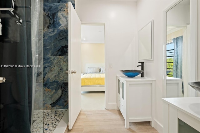 bathroom with hardwood / wood-style flooring, a tile shower, vanity, and crown molding