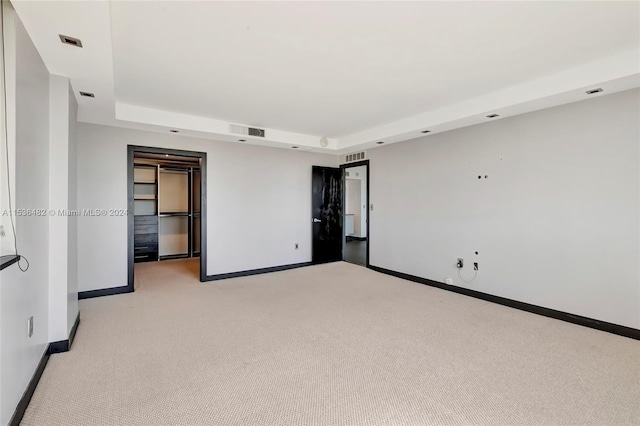 carpeted spare room with a raised ceiling