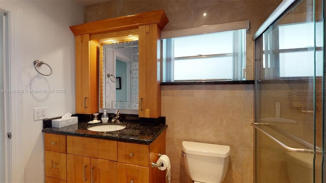 bathroom featuring a shower with door, vanity, a wealth of natural light, and toilet